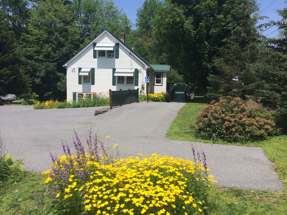 The parking lot of the Richmond Pediatrics office. The parking lot is paved and there is an International Symbol of Access sign in the parking spot nearest to the office entrance.