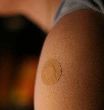 A circular bandaid on a shoulder.